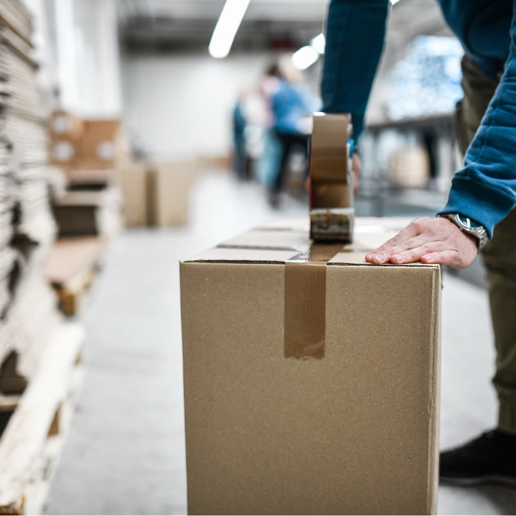 male-worker-taping-cardboard-box